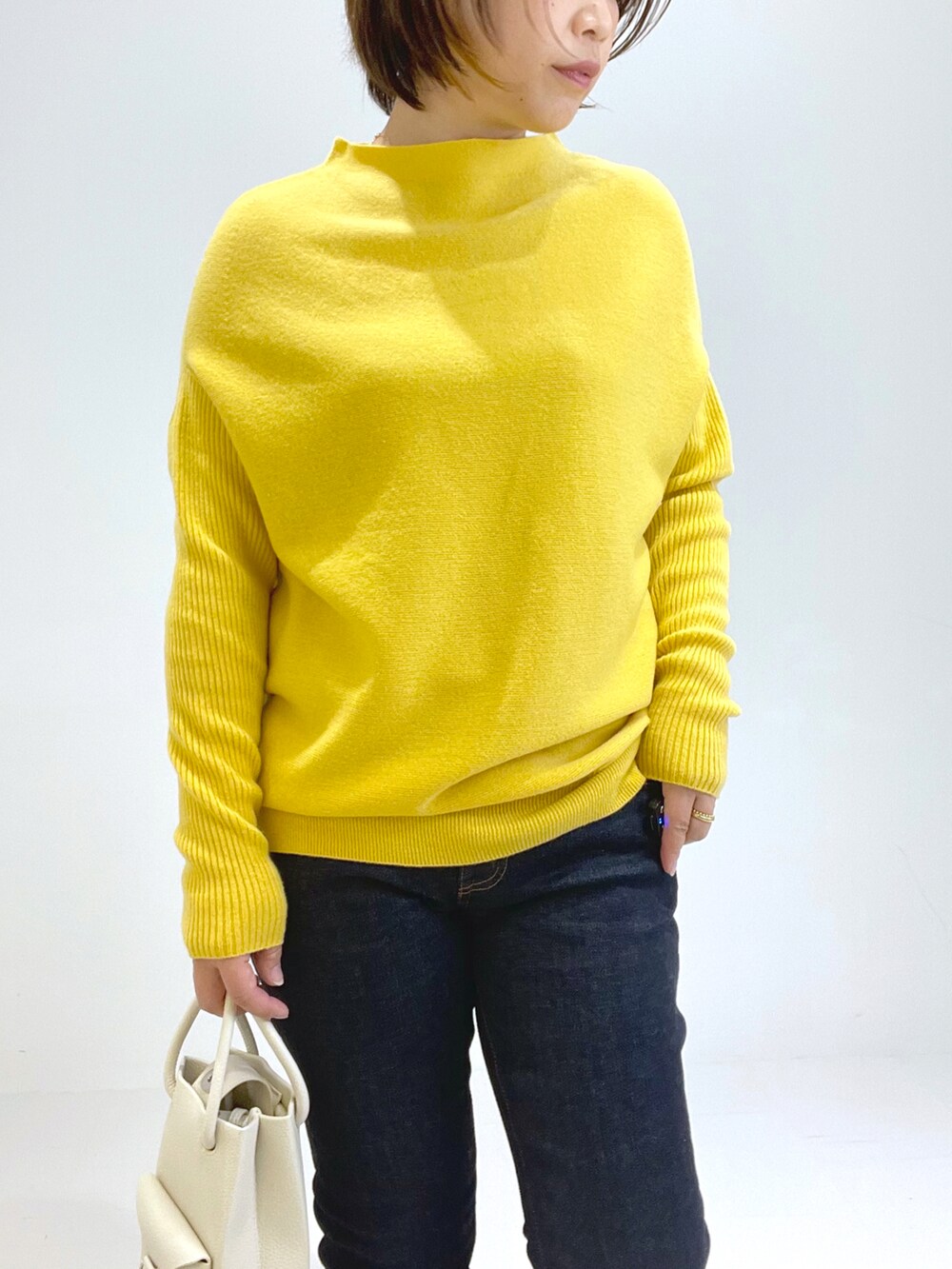 ブラック系のブーツ、イエロー系のトートバッグ、イエロー系のニット/セーターを着用したレディースの秋コーディネートの2枚目の写真