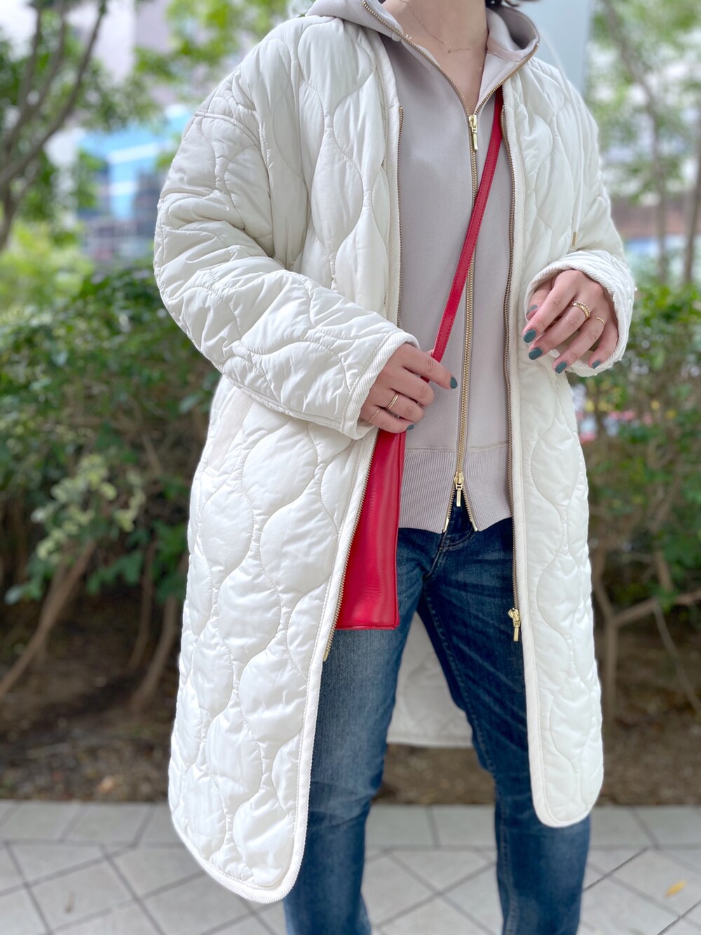 ブルー系のデニムパンツ、ブラック系のブーツ、ベージュ系のパーカーを着用したレディースの秋コーディネートの2枚目の写真