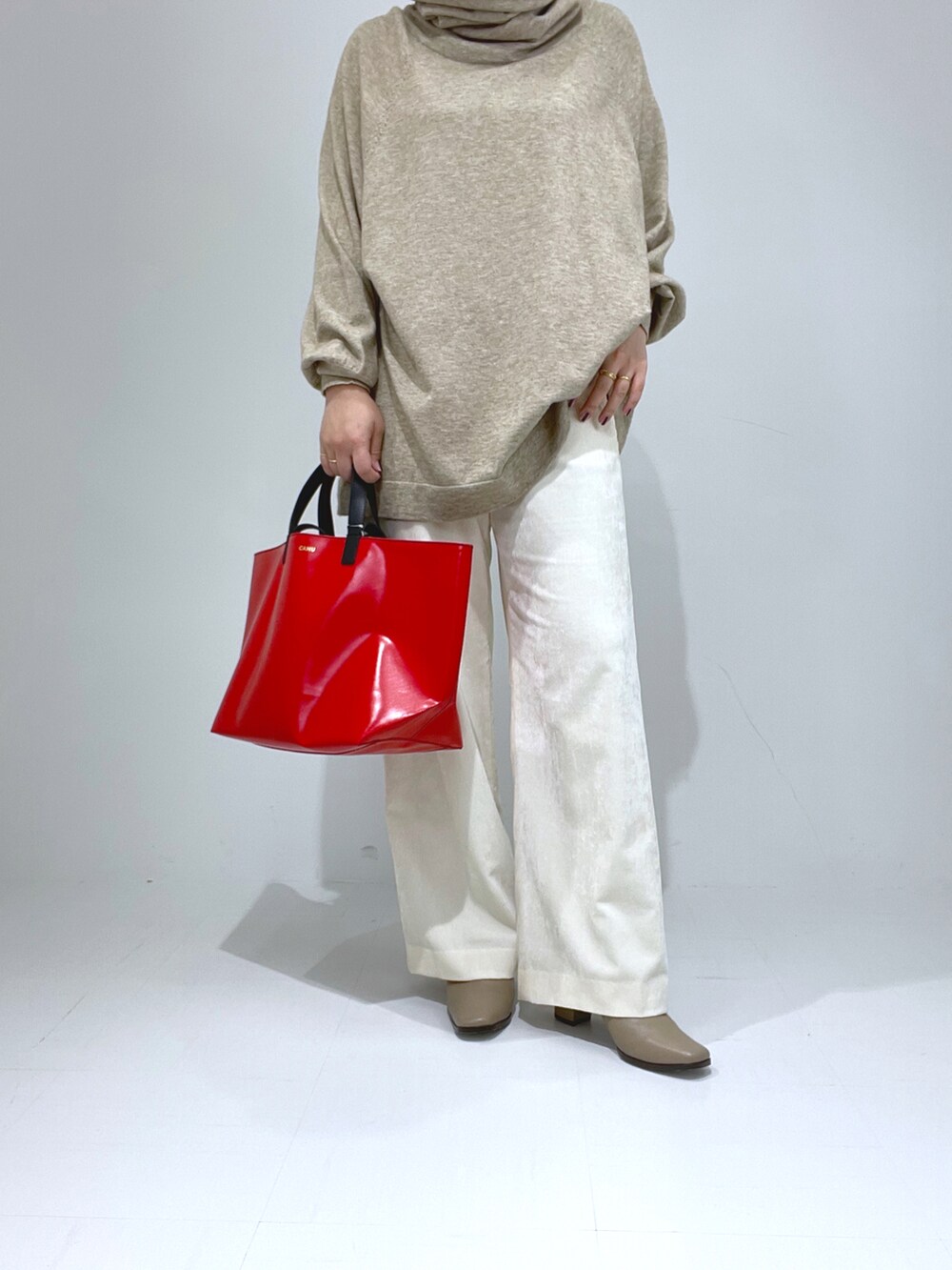 レッド系のトートバッグ、ホワイト系のその他パンツ、ベージュ系のブーツを着用したレディースの冬コーディネートの3枚目の写真