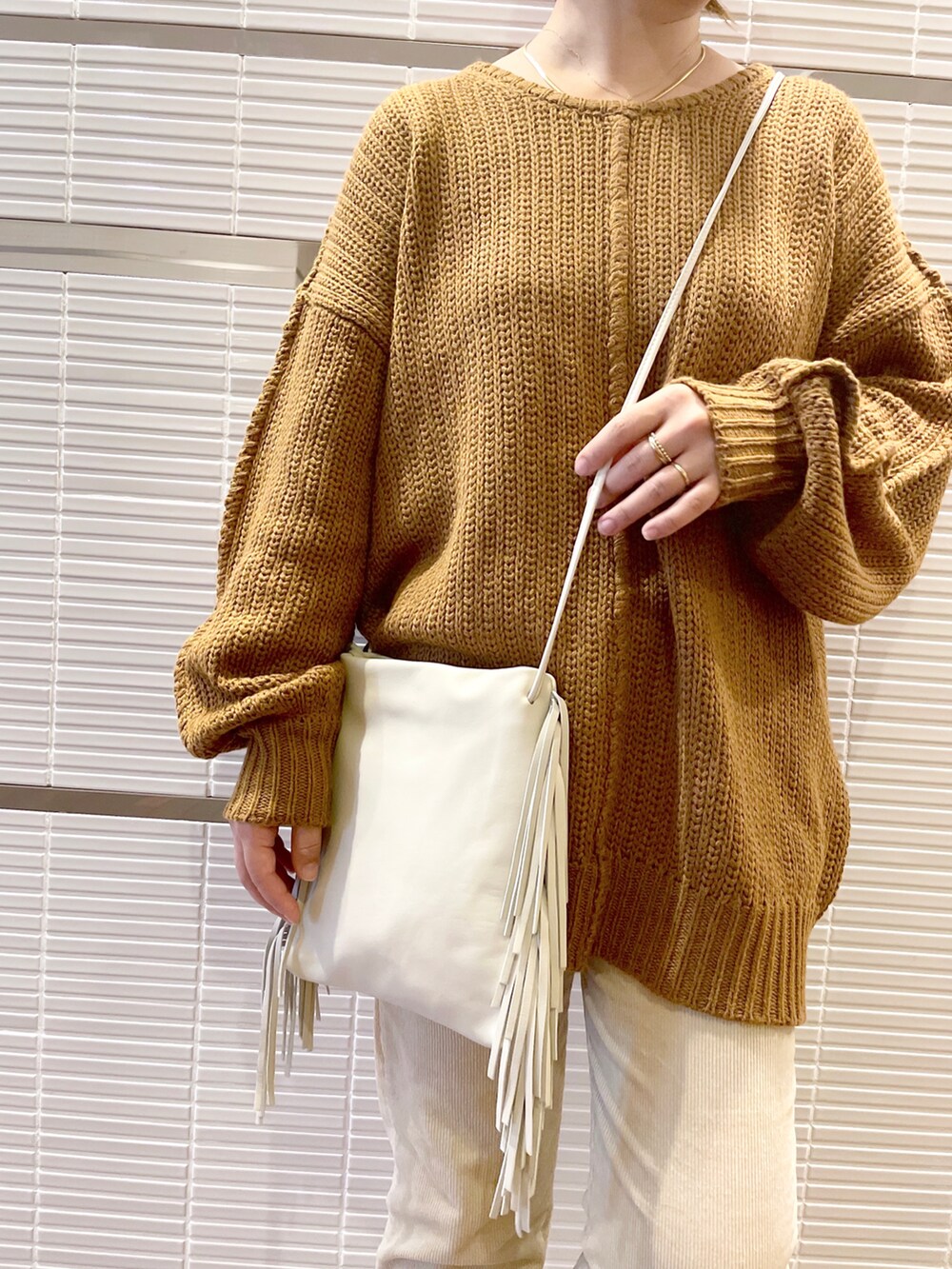 ホワイト系のデニムパンツ、ホワイト系のショルダーバッグ、ブラウン系のニット/セーターを着用したレディースの秋コーディネートの3枚目の写真