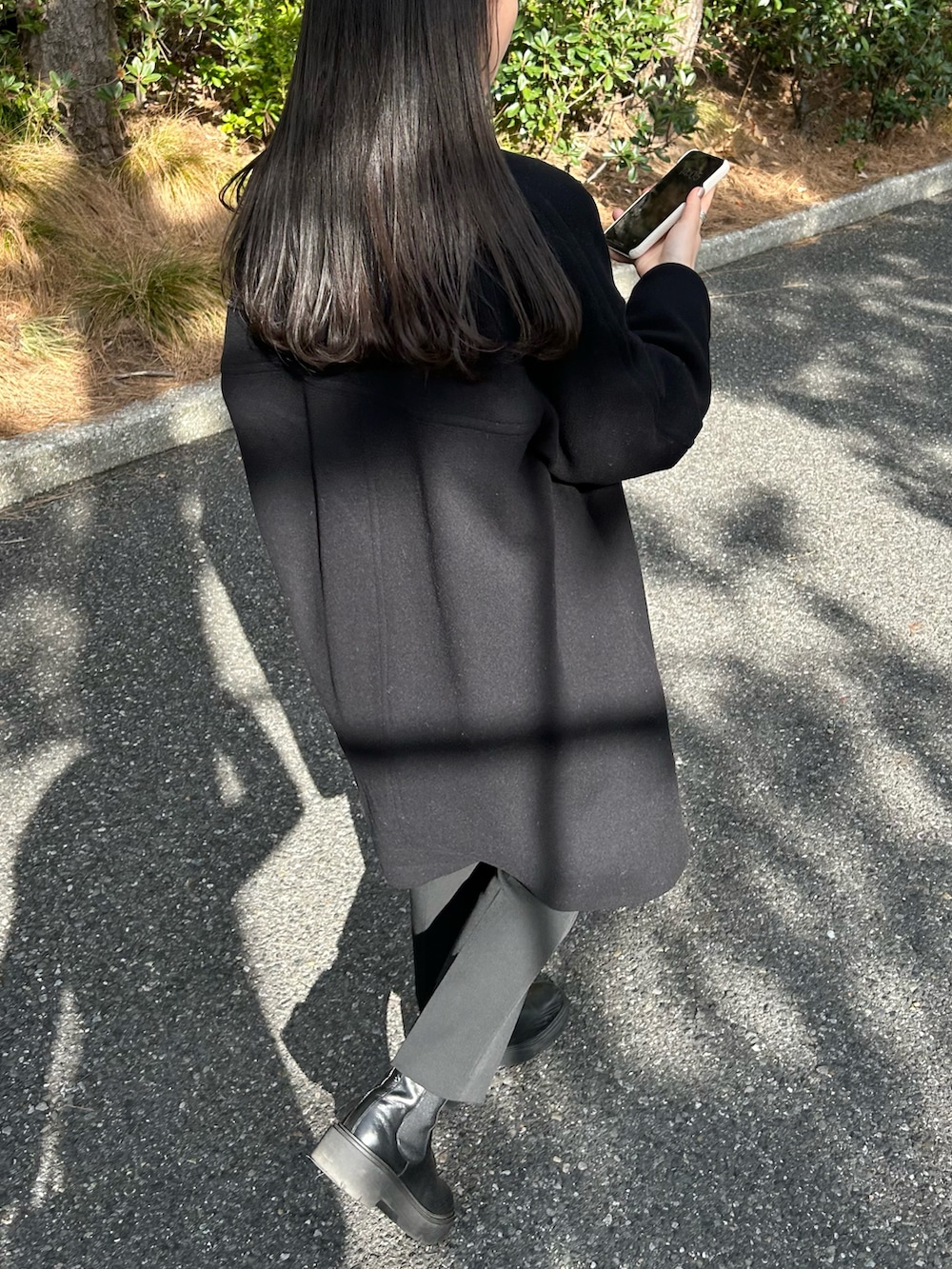 ブラック系のノーカラーコート、ブラック系のショルダーバッグ、グレー系のカーディガン/ボレロを着用したレディースの冬コーディネートの3枚目の写真