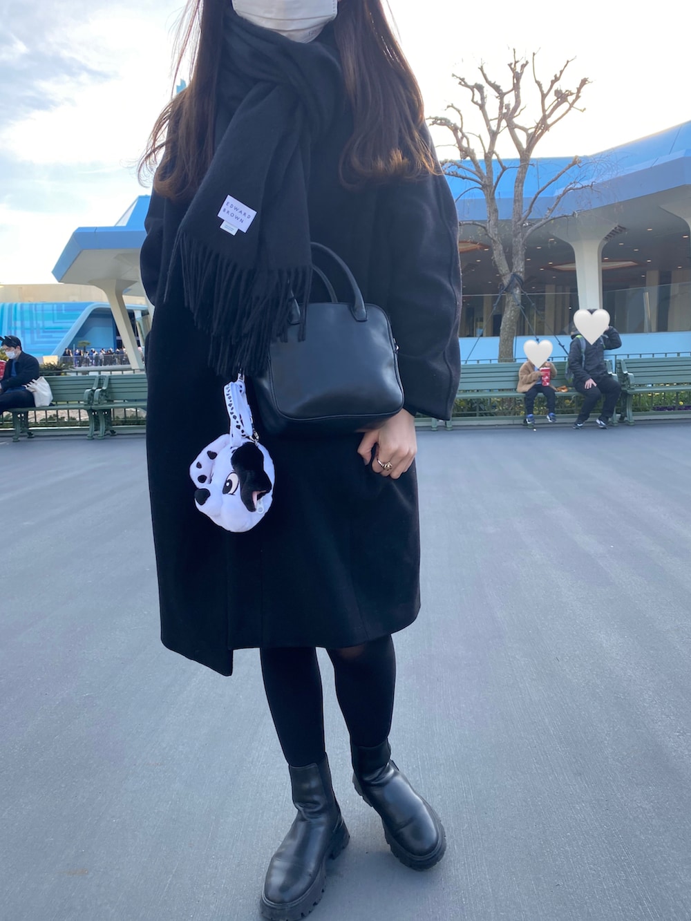 ブラック系のノーカラーコート、ブルー系のデニムスカート、ブラック系のハンドバッグを着用したレディースの冬コーディネートの2枚目の写真