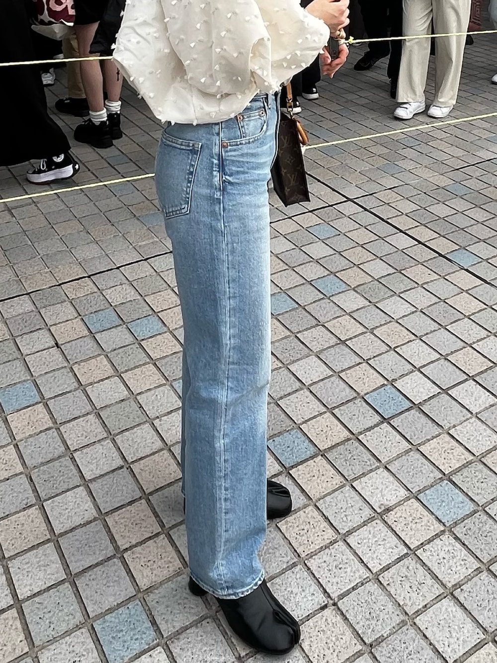 ブルー系のデニムパンツ、ブラック系のブーツを着用したレディースの春コーディネートの2枚目の写真