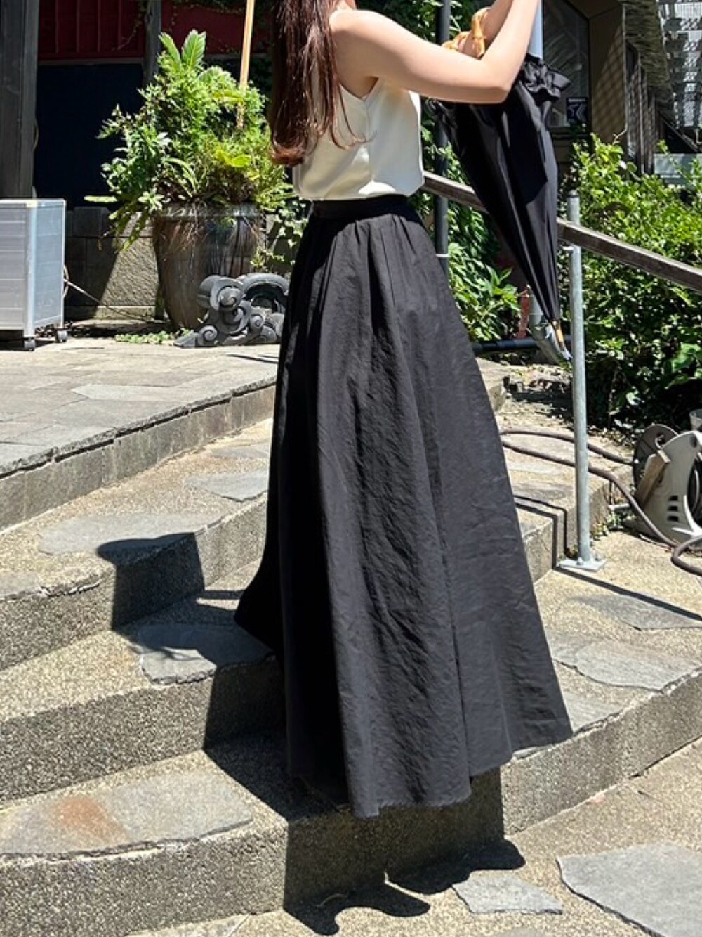 ホワイト系のキャミソール、ブラック系のスカート、ブラウン系のバレエシューズを着用したレディースの秋コーディネートの2枚目の写真