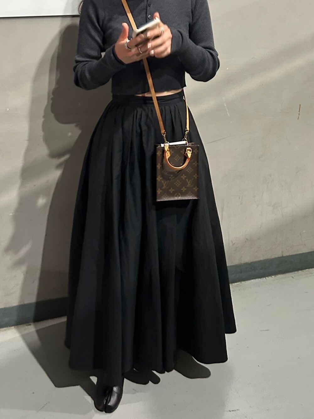 グレー系のカーディガン/ボレロ、ブラック系のスカート、ブラック系のブーツを着用したレディースの冬コーディネートの3枚目の写真