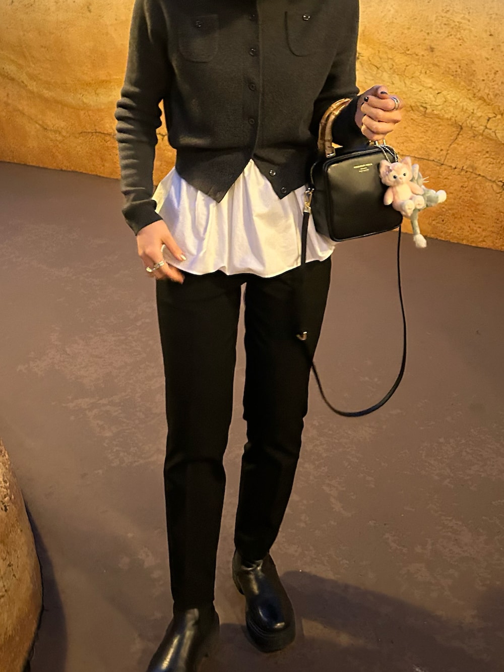 ブラック系のノーカラーコート、ブラック系のショルダーバッグ、グレー系のカーディガン/ボレロを着用したレディースの冬コーディネートの4枚目の写真