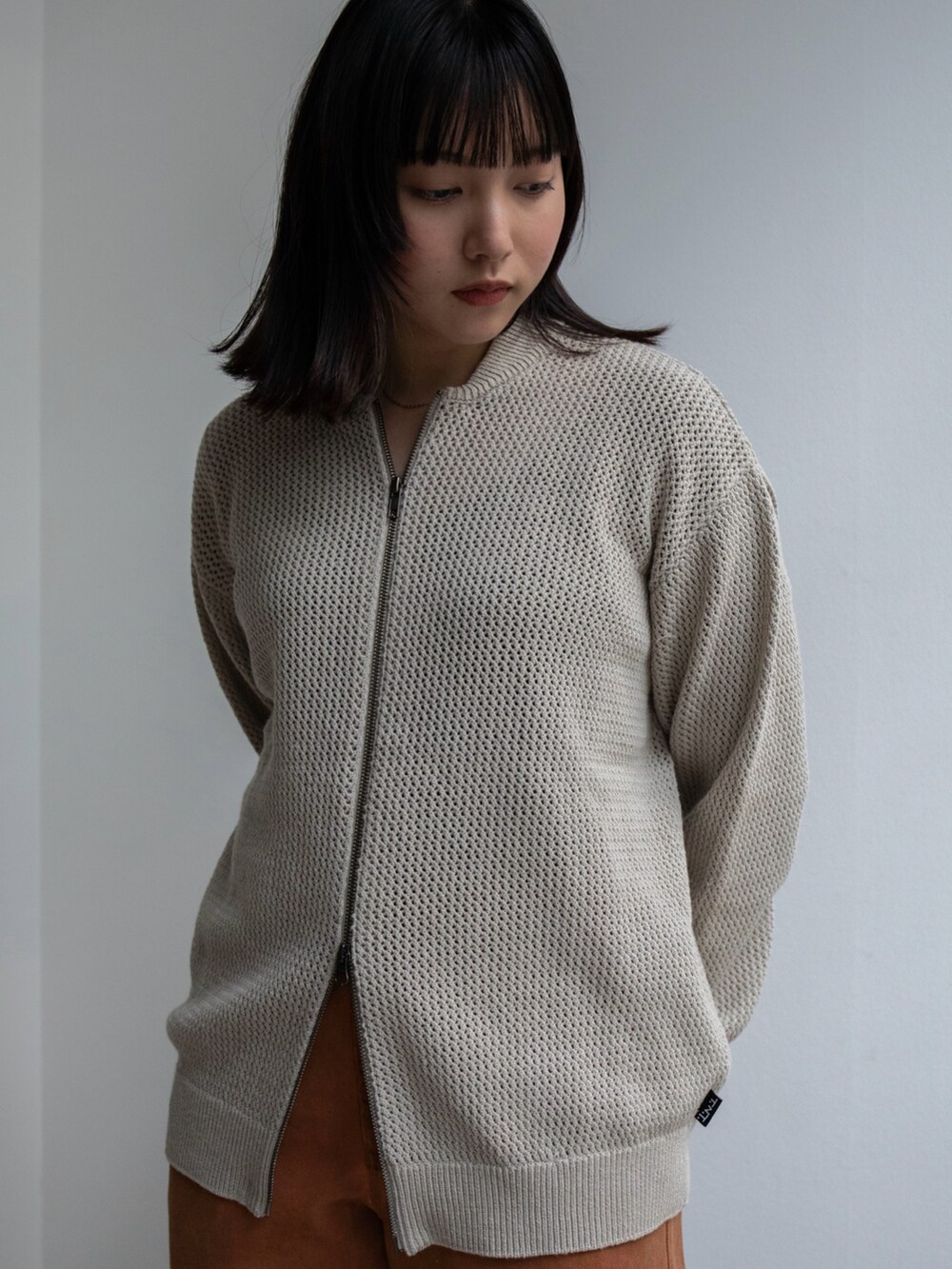 オレンジ系のその他パンツ、ベージュ系のカーディガン/ボレロを着用したレディースの冬コーディネートの2枚目の写真