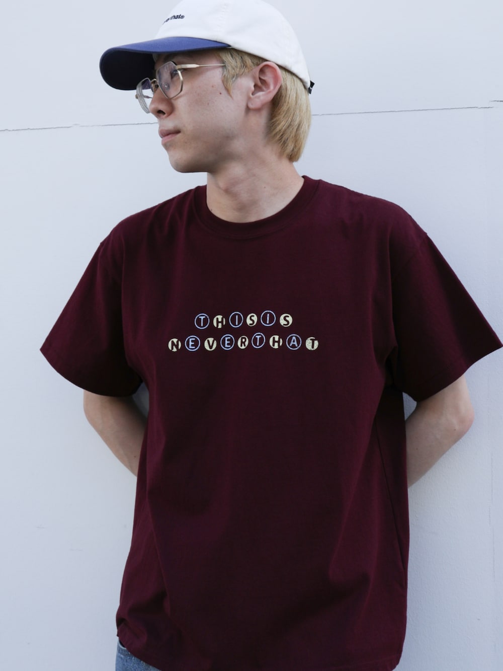 ブルー系のデニムパンツ、レッド系のTシャツ/カットソー、ホワイト系のキャップを着用したメンズの夏コーディネートの2枚目の写真