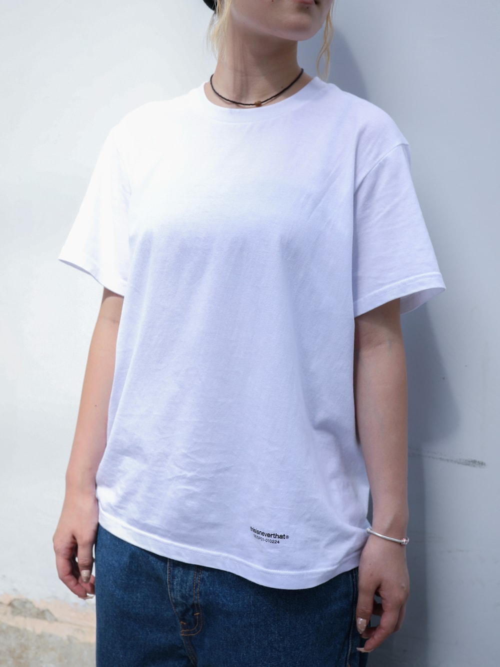 ブルー系のデニムパンツ、ホワイト系のTシャツ/カットソー、ブラック系のニットキャップ/ビーニーを着用したレディースの夏コーディネートの2枚目の写真