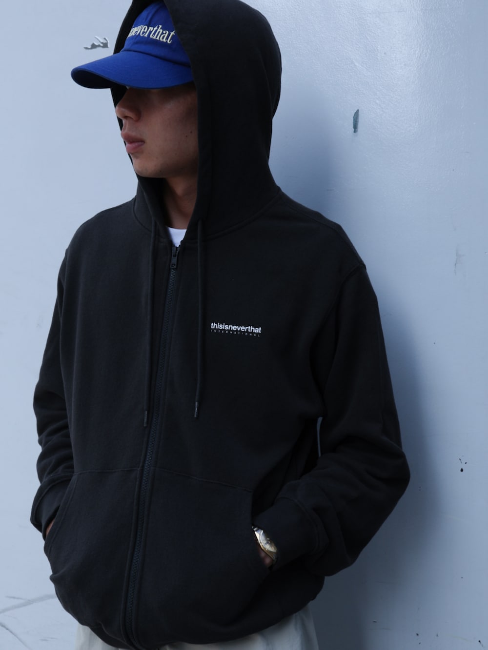ブラック系のパーカー、ベージュ系のその他パンツ、ブルー系のキャップを着用したメンズの夏コーディネートの2枚目の写真