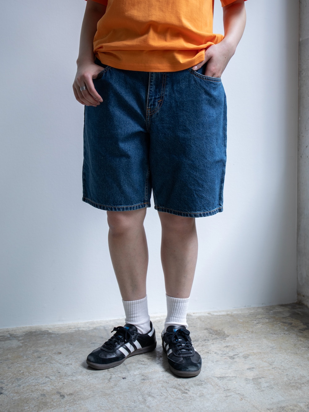 オレンジ系のTシャツ/カットソー、ブルー系のデニムパンツを着用したレディースの春コーディネートの4枚目の写真