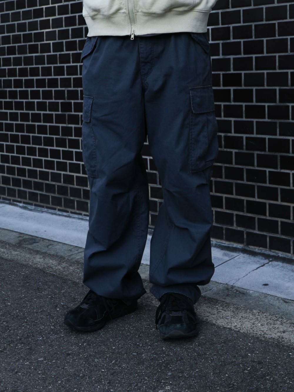 イエロー系のパーカー、ブルー系のカーゴパンツ、ブラック系のニットキャップ/ビーニーを着用したメンズの秋コーディネートの5枚目の写真