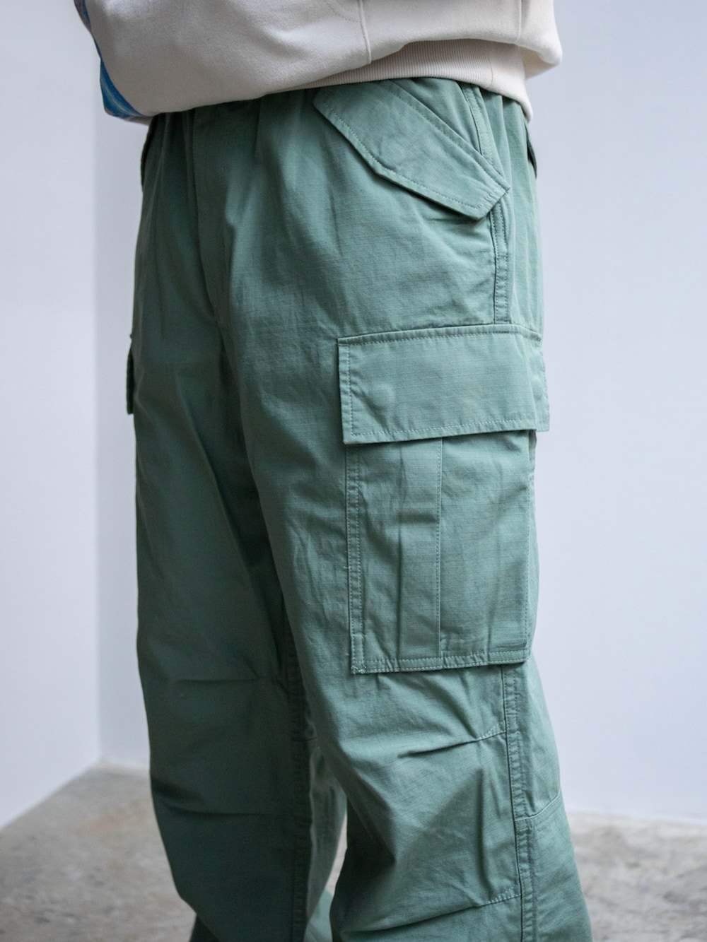 ベージュ系のパーカー、グリーン系のカーゴパンツ、グリーン系のニットキャップ/ビーニーを着用したメンズの春コーディネートの4枚目の写真