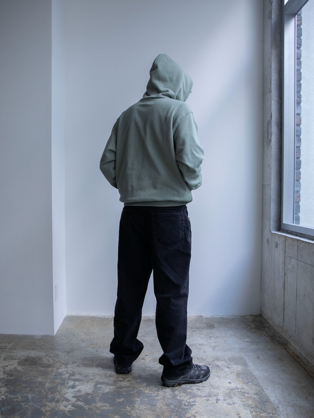 グリーン系のパーカー、ブラック系のデニムパンツを着用したメンズの春コーディネートの2枚目の写真