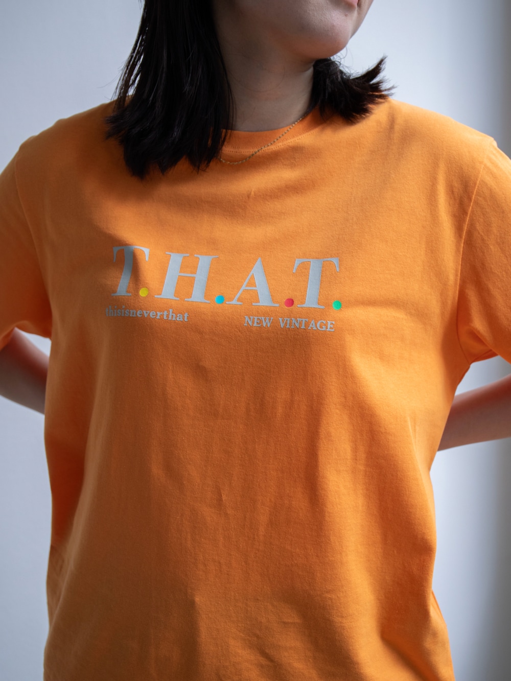 オレンジ系のTシャツ/カットソー、ブルー系のデニムパンツを着用したレディースの春コーディネートの3枚目の写真