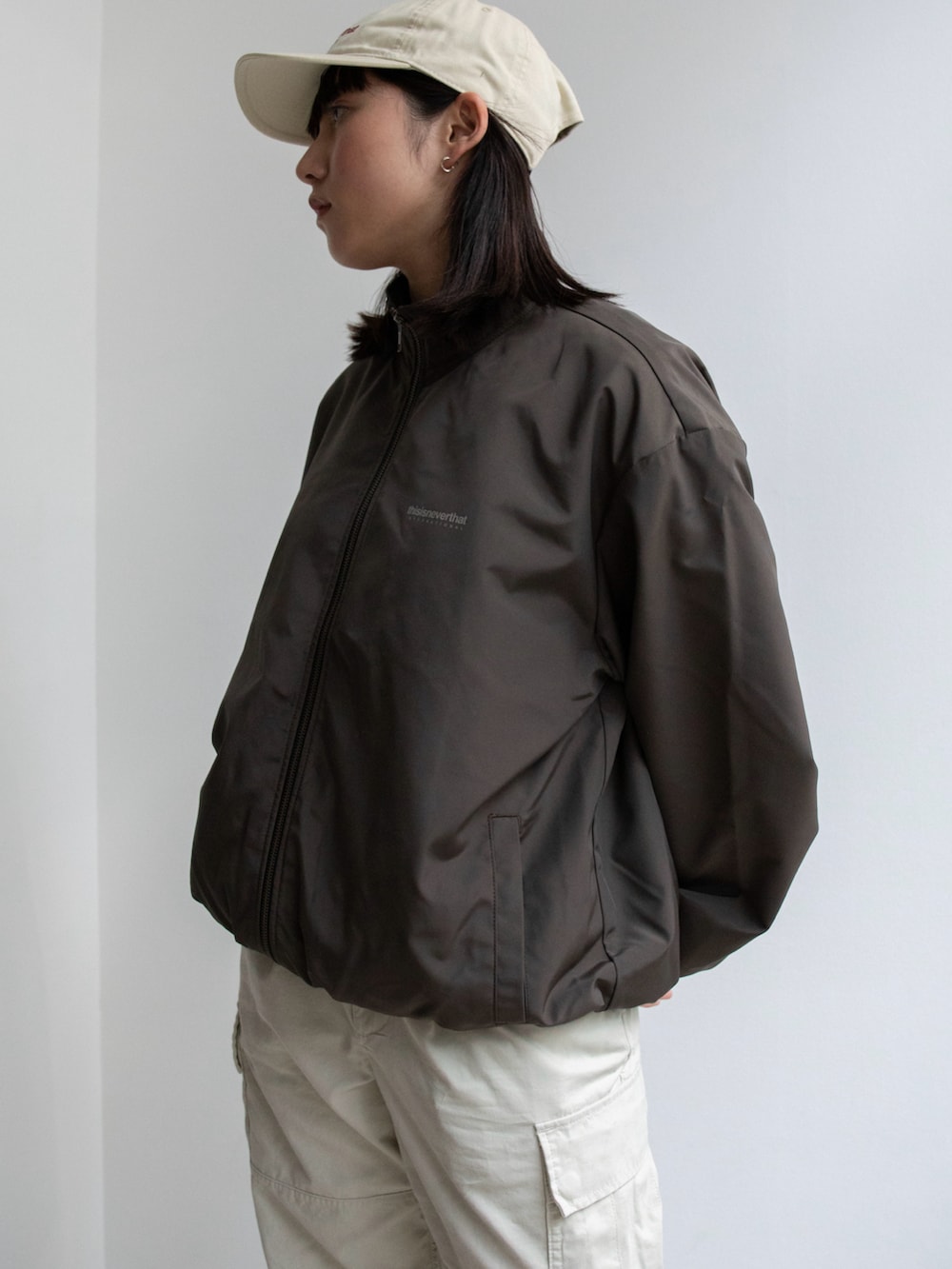 ブラウン系のブルゾン、ホワイト系のその他パンツ、ホワイト系のキャップを着用したレディースの冬コーディネートの2枚目の写真