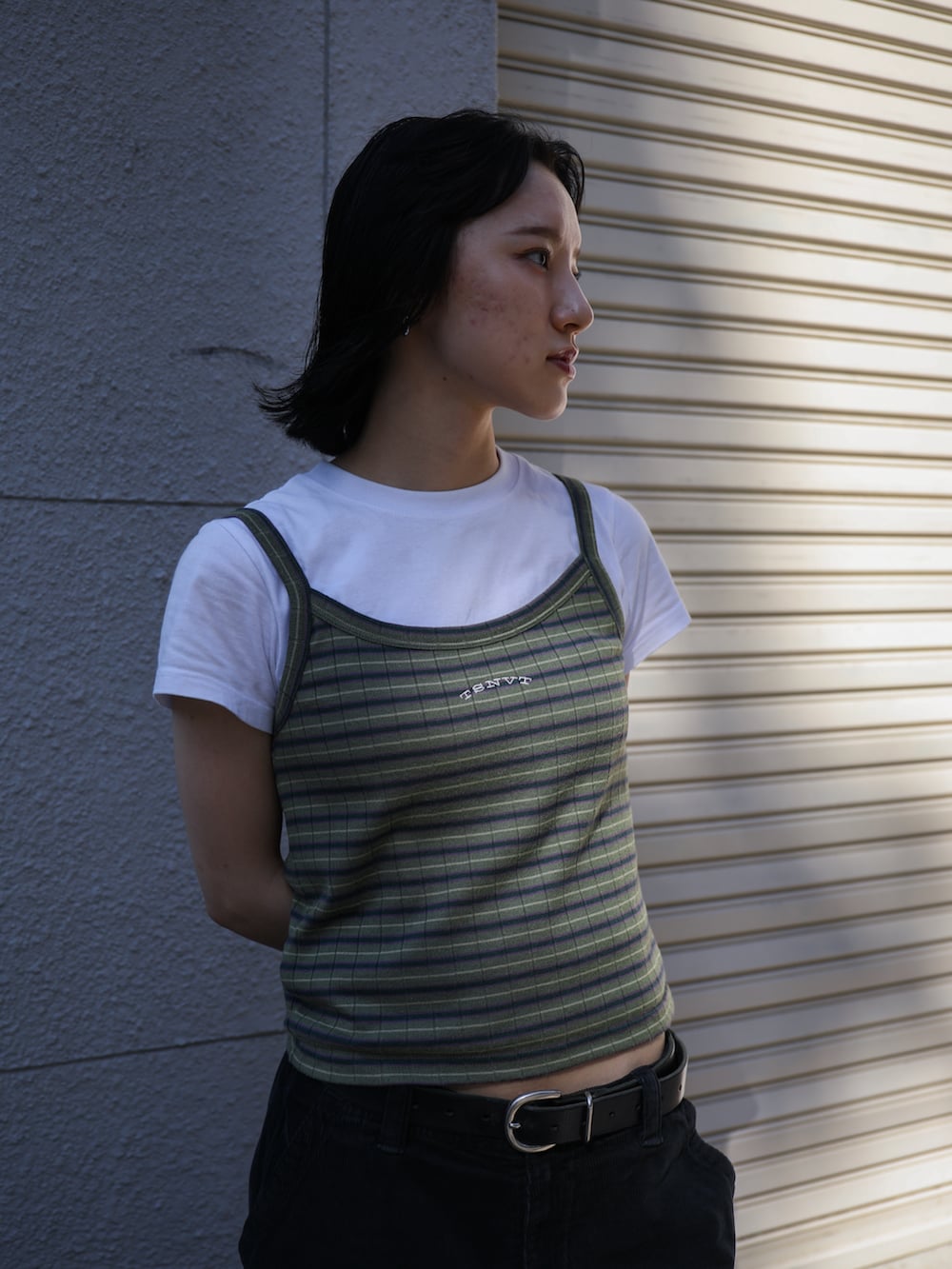 グリーン系のキャミソール、ブラック系のカーゴパンツ、ホワイト系のTシャツ/カットソーを着用したレディースの春コーディネートの2枚目の写真