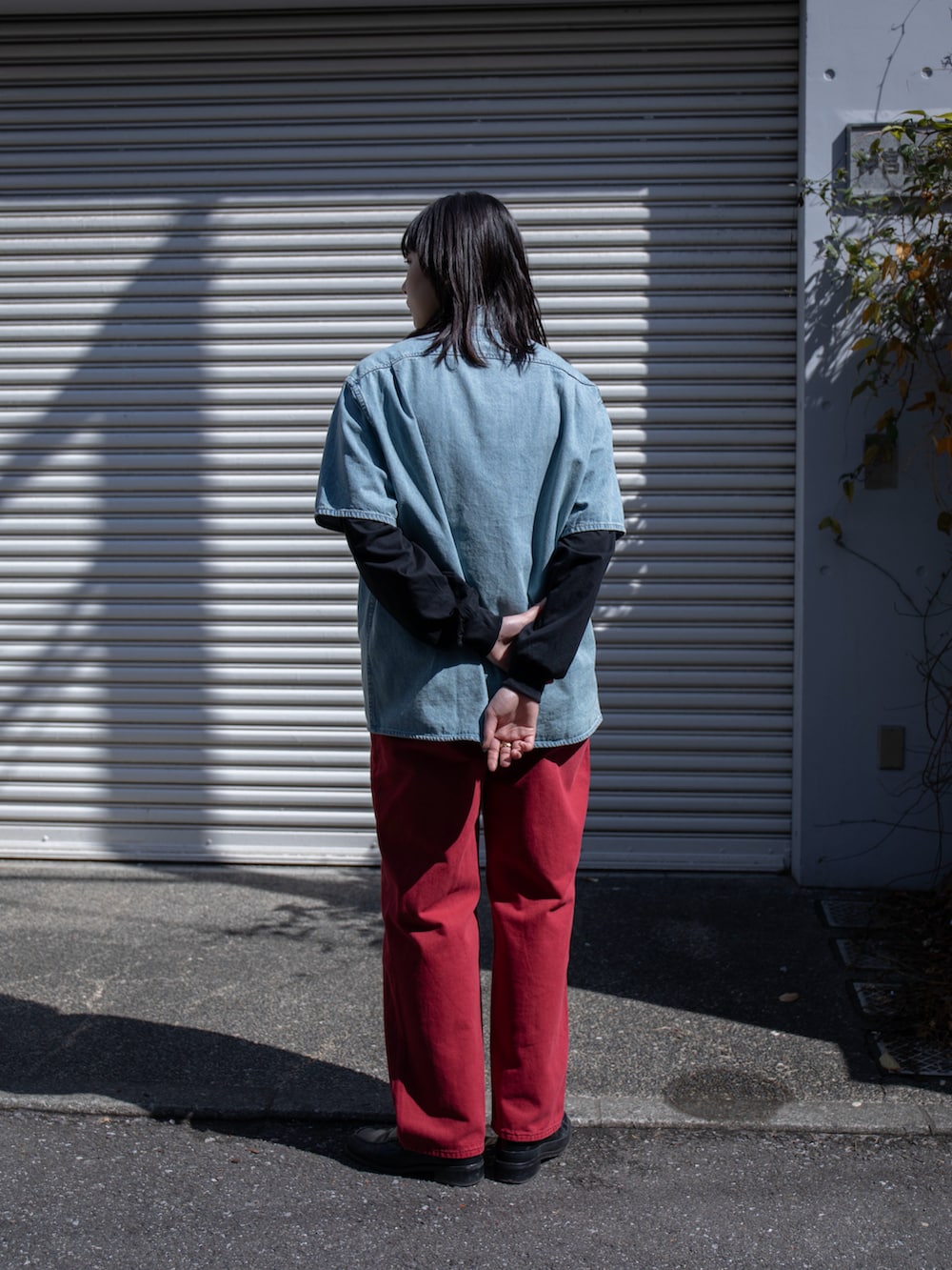 レッド系のデニムパンツ、ブルー系のシャツ/ブラウス、ブラック系のTシャツ/カットソーを着用したレディースの春コーディネートの2枚目の写真