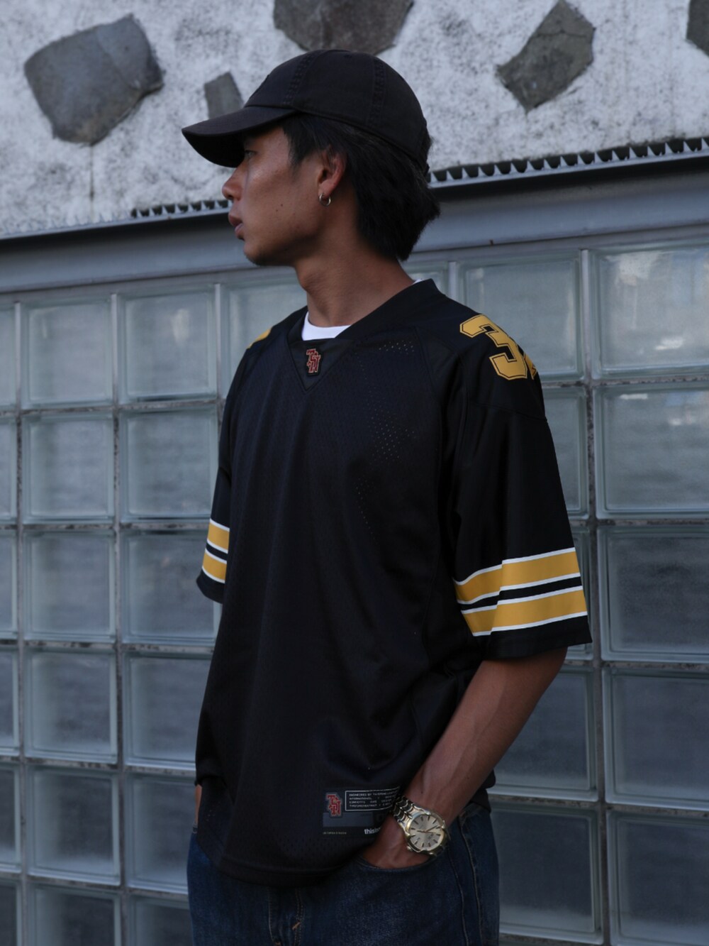 ブラック系のTシャツ/カットソー、ブルー系のデニムパンツ、ブラック系のキャップを着用したメンズの夏コーディネートの2枚目の写真
