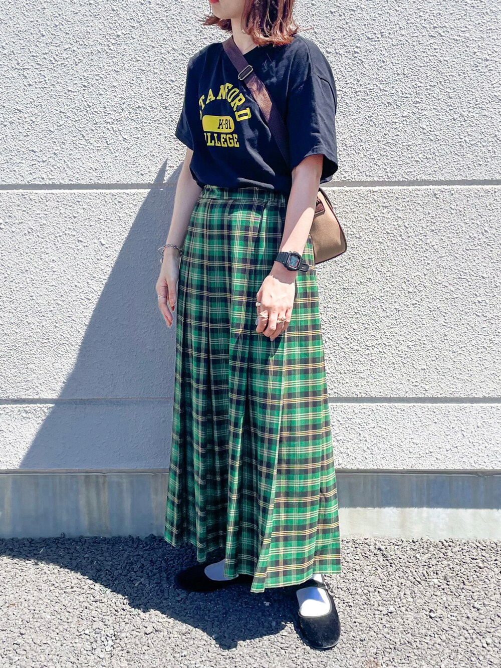 グリーン系のスカート、ブラック系のTシャツ/カットソー、ブラウン系のショルダーバッグを着用したレディースの夏コーディネートの2枚目の写真