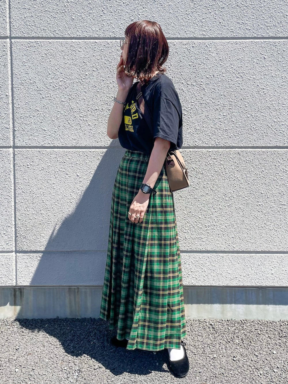 グリーン系のスカート、ブラック系のTシャツ/カットソー、ブラウン系のショルダーバッグを着用したレディースの夏コーディネートの3枚目の写真