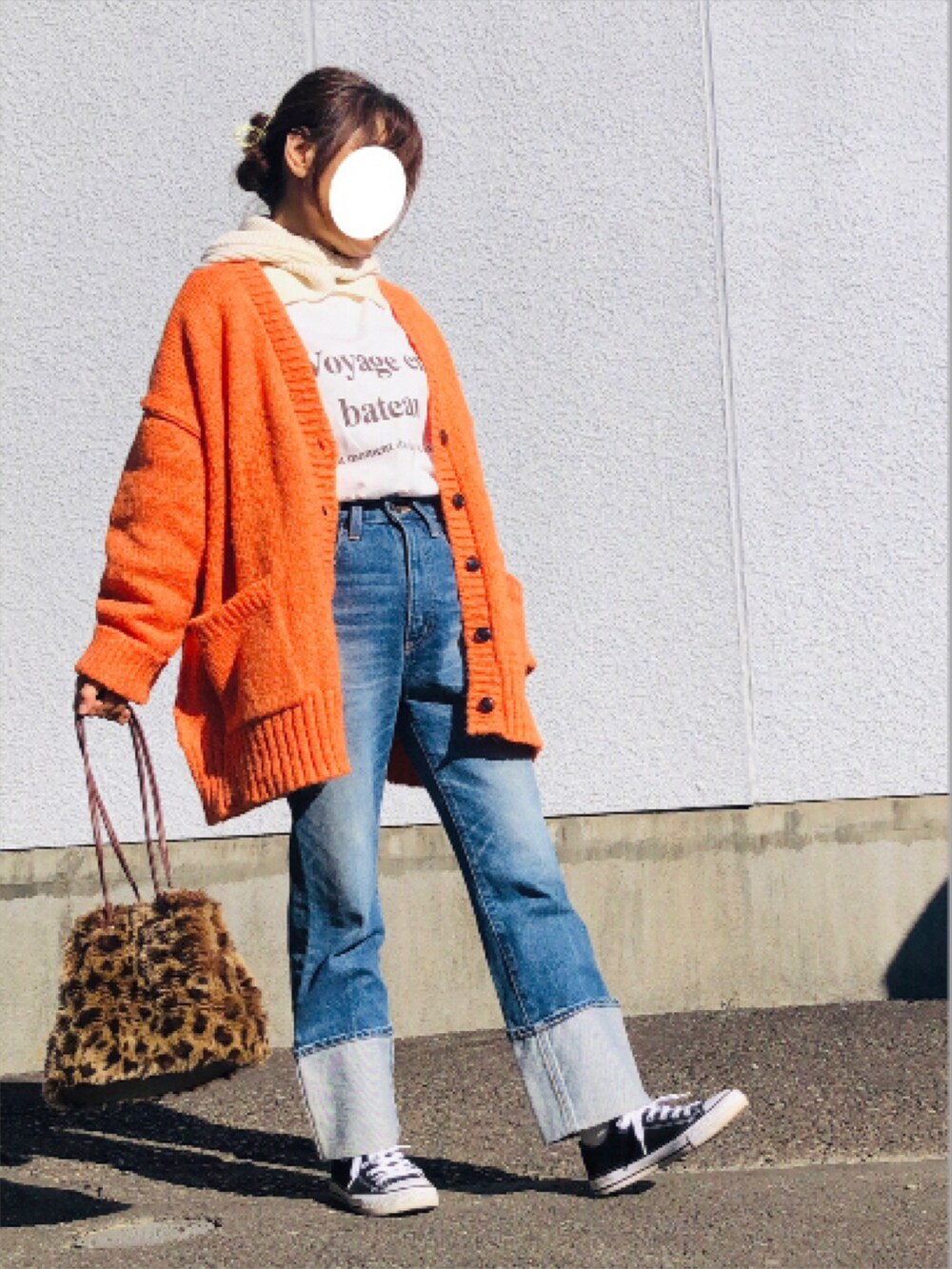 オレンジ系のカーディガン/ボレロ、ホワイト系のTシャツ/カットソー、ブルー系のデニムパンツを着用したレディースの冬コーディネートの2枚目の写真