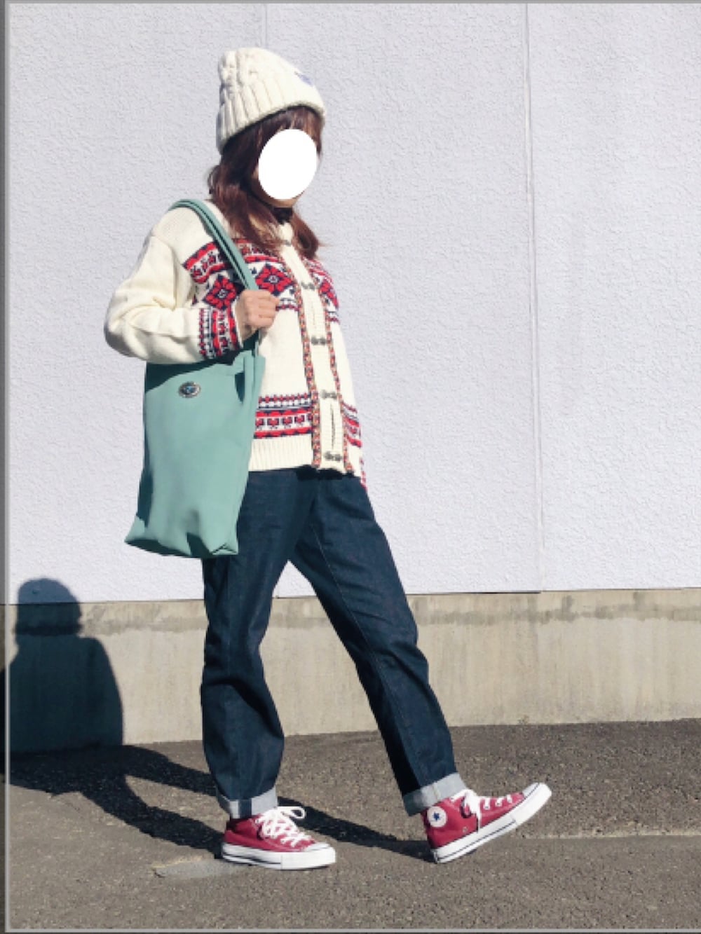 ベージュ系のカーディガン/ボレロ、レッド系のニット/セーター、ブルー系のデニムパンツを着用したレディースの冬コーディネートの2枚目の写真