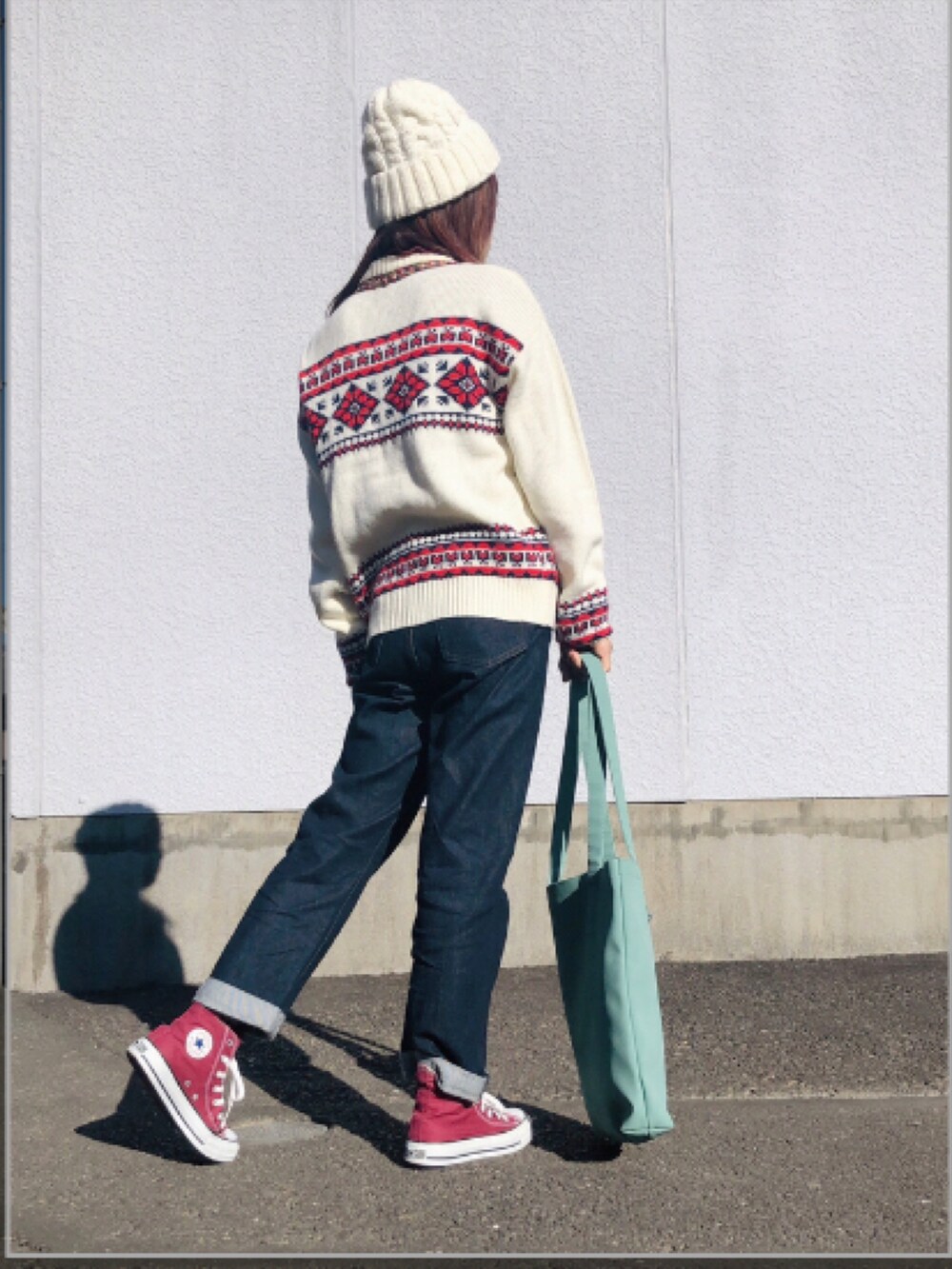 ベージュ系のカーディガン/ボレロ、レッド系のニット/セーター、ブルー系のデニムパンツを着用したレディースの冬コーディネートの3枚目の写真