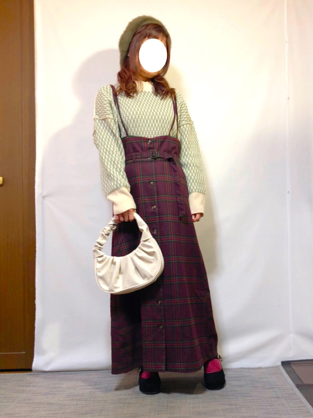 グリーン系のニット/セーター、レッド系のジャンパースカート、ブラック系のパンプスを着用したレディースの冬コーディネートの2枚目の写真