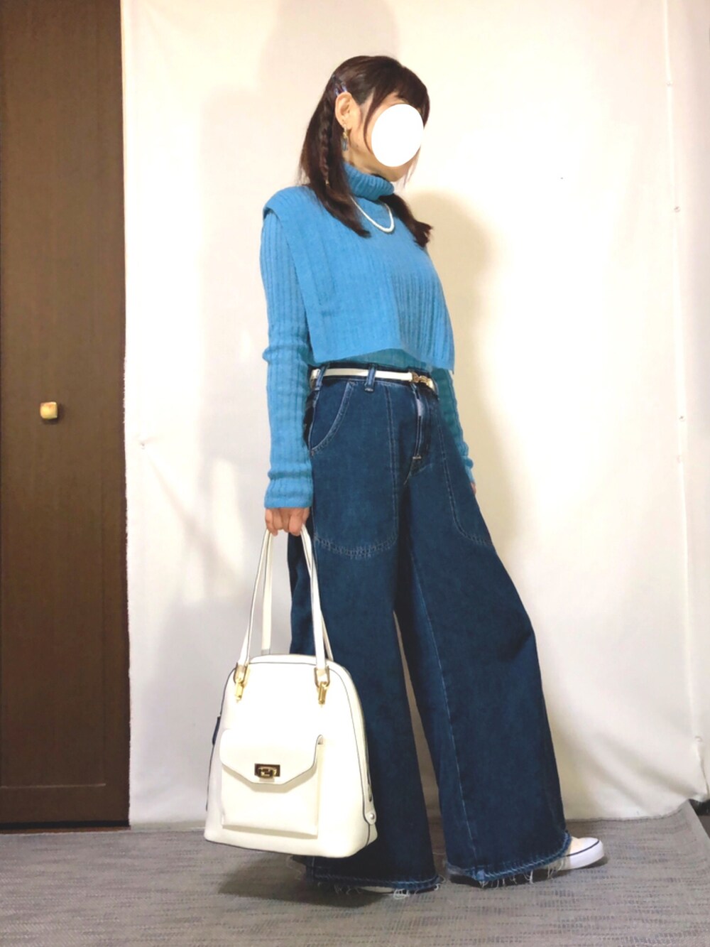 ブルー系のニット/セーター、ブルー系のデニムパンツ、ホワイト系のスニーカーを着用したレディースの春コーディネートの2枚目の写真