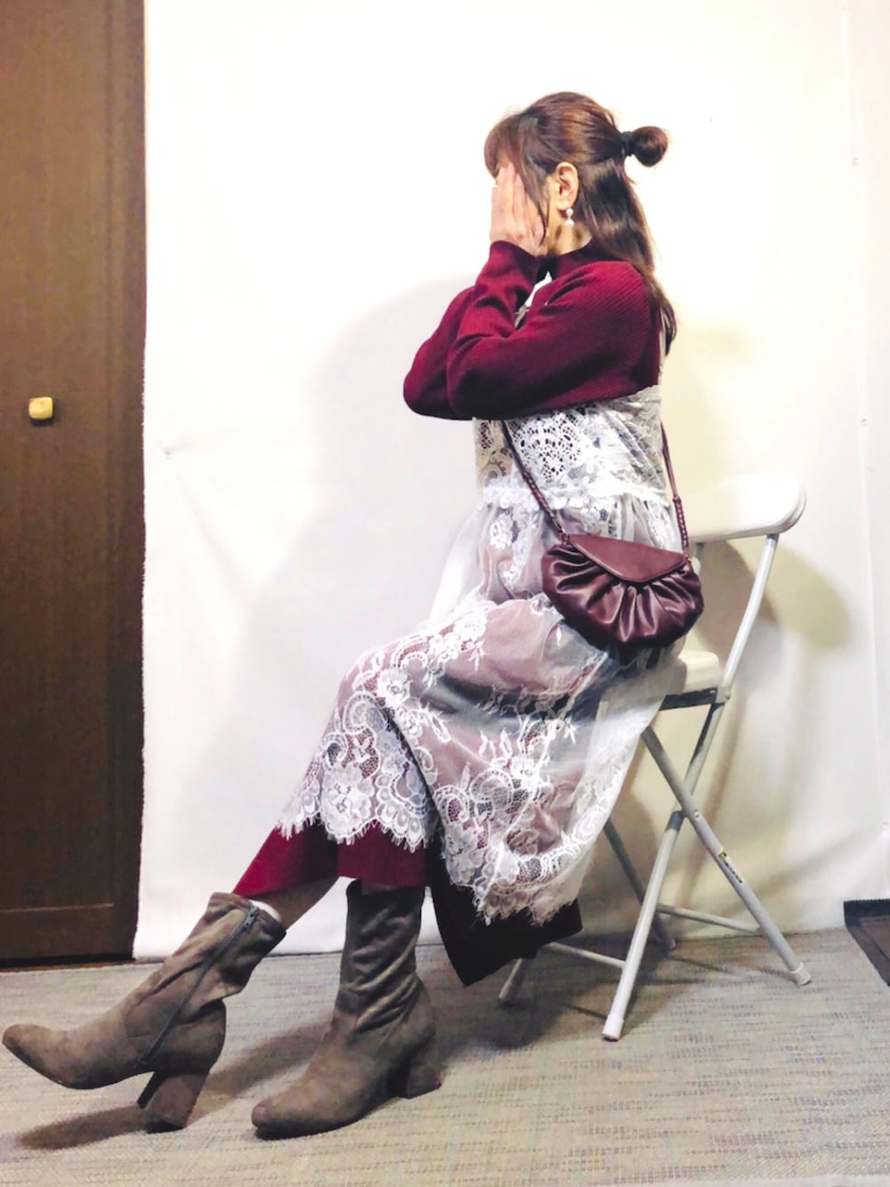 レッド系のワンピース、グレー系のブーツ、ブラウン系のショルダーバッグを着用したレディースの春コーディネートの2枚目の写真