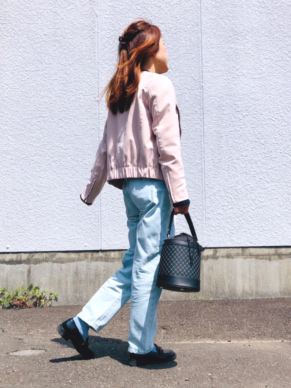 ピンク系のライダースジャケット、ブルー系のニット/セーター、ブルー系のデニムパンツを着用したレディースの春コーディネートの3枚目の写真