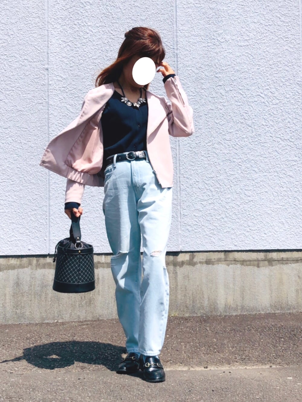 ピンク系のライダースジャケット、ブルー系のニット/セーター、ブルー系のデニムパンツを着用したレディースの春コーディネートの2枚目の写真