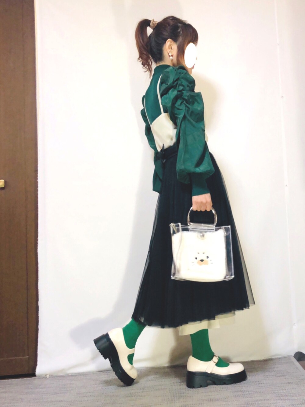 グリーン系のニット/セーター、ホワイト系のジャンパースカート、ブラック系のスカートを着用したレディースの秋コーディネートの3枚目の写真
