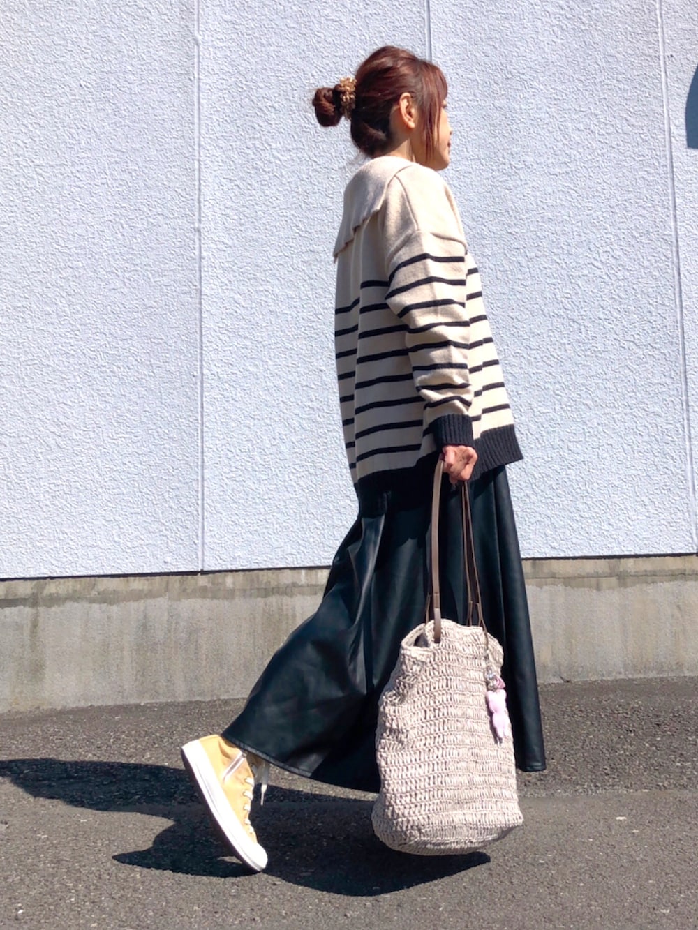 ベージュ系のニット/セーター、ブラウン系のTシャツ/カットソー、ブラック系のスカートを着用したレディースの春コーディネートの2枚目の写真