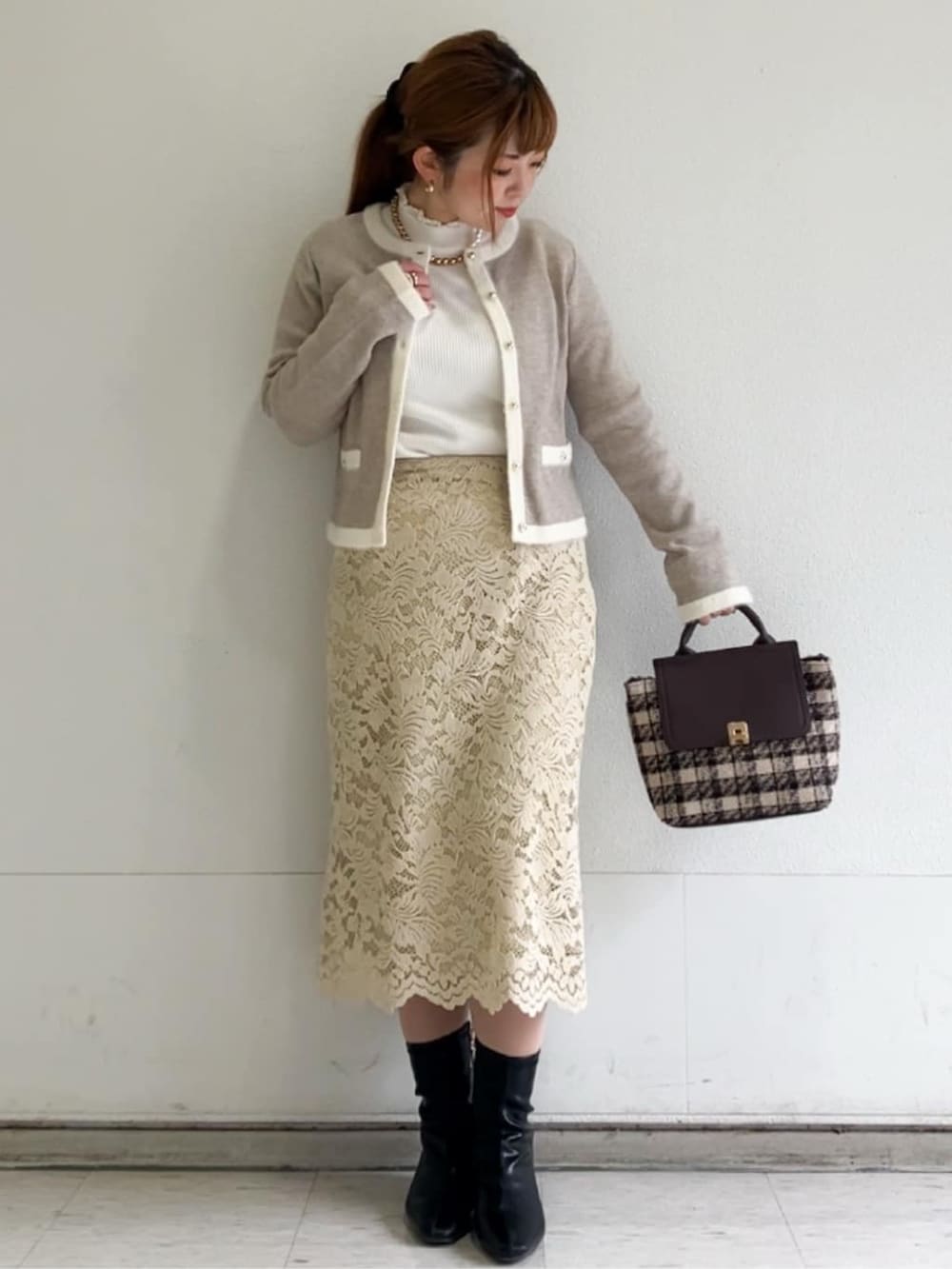 ベージュ系のカーディガン/ボレロ、ホワイト系のニット/セーター、イエロー系のスカートを着用したレディースの冬コーディネートの6枚目の写真
