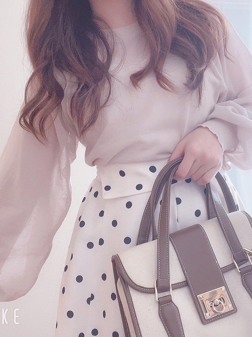 ホワイト系のスカート、ベージュ系のバッグ、ベージュ系のトップスを着用したレディースの夏コーディネートの3枚目の写真