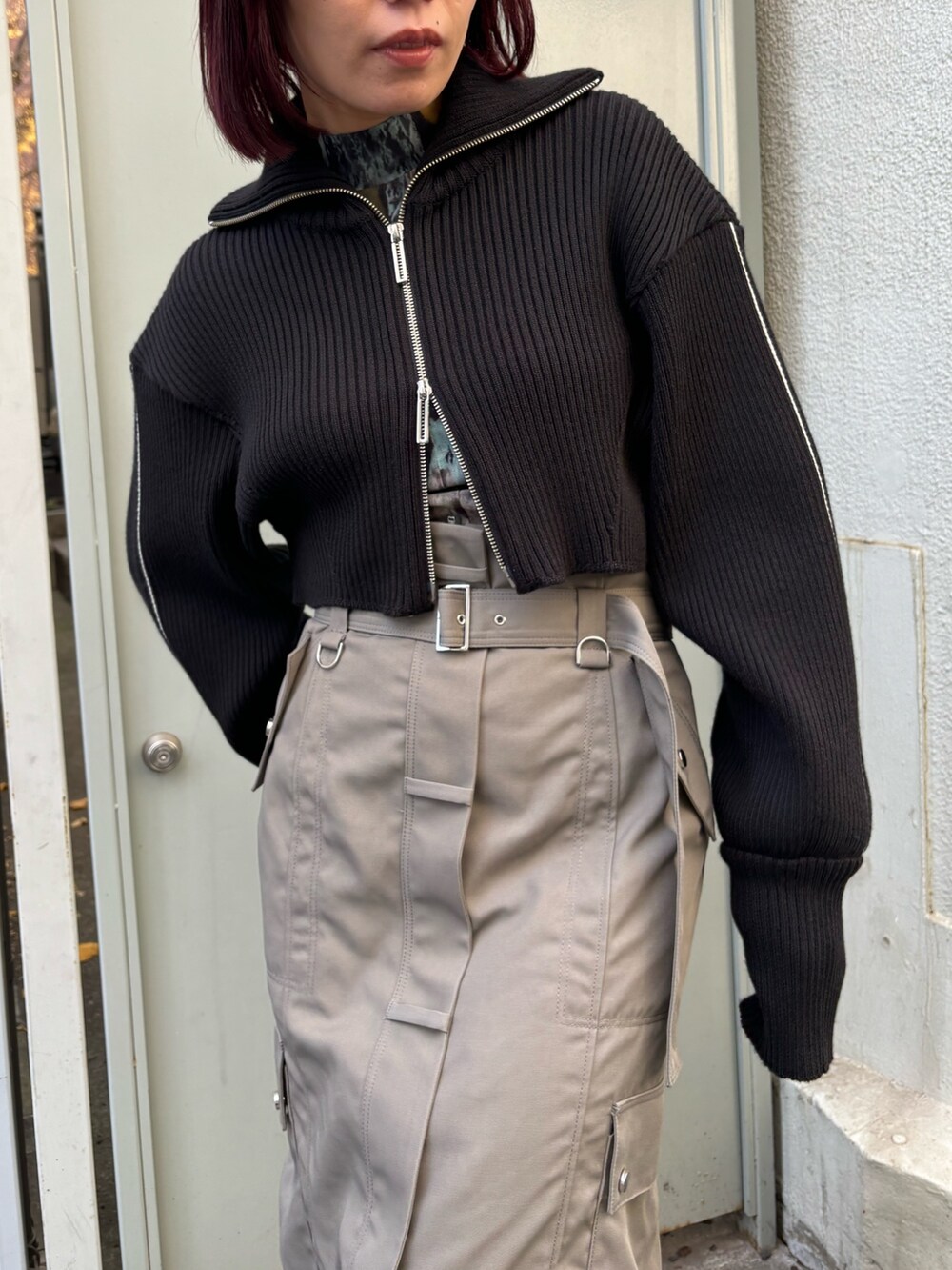 ブラック系のニット/セーター、ブラウン系のTシャツ/カットソー、グレー系のスカートを着用したレディースの冬コーディネートの6枚目の写真