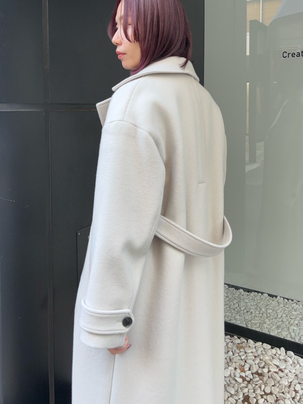 ホワイト系のステンカラーコートを着用したレディースの冬コーディネートの4枚目の写真