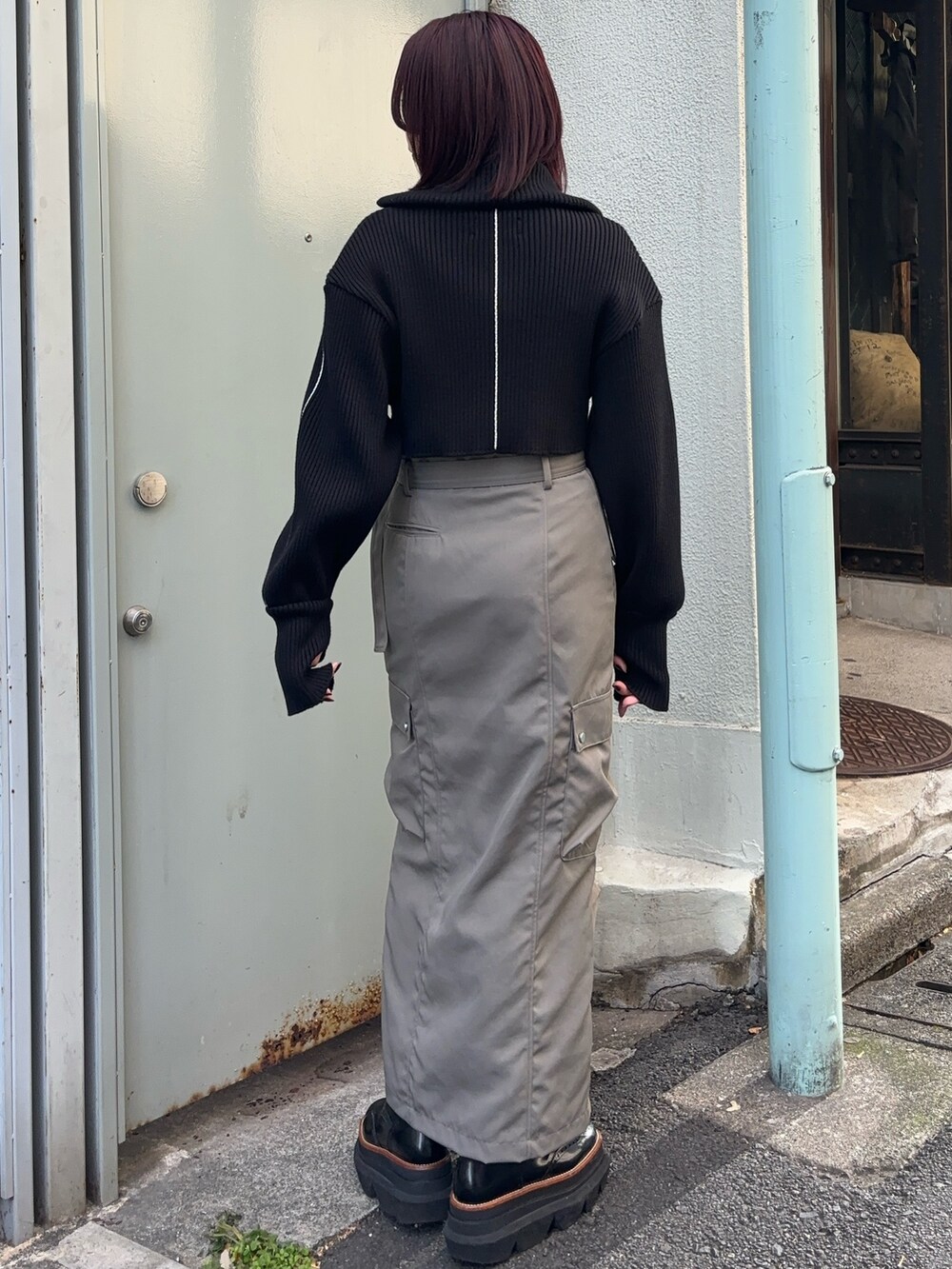 ブラック系のニット/セーター、ブラウン系のTシャツ/カットソー、グレー系のスカートを着用したレディースの冬コーディネートの2枚目の写真