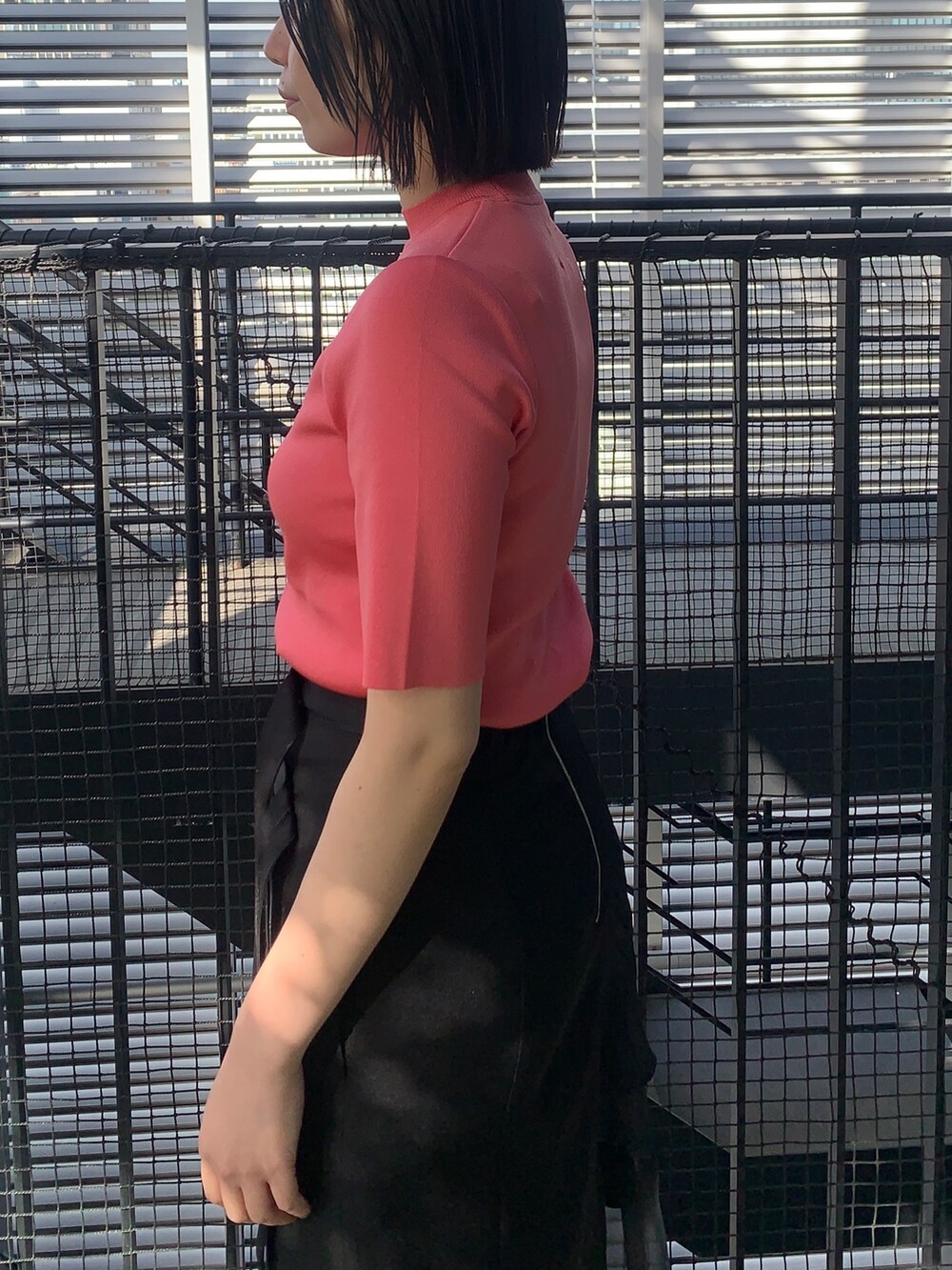 ピンク系のニット/セーター、ブラック系のスカート、ブラック系のその他シューズを着用したレディースの春コーディネートの5枚目の写真