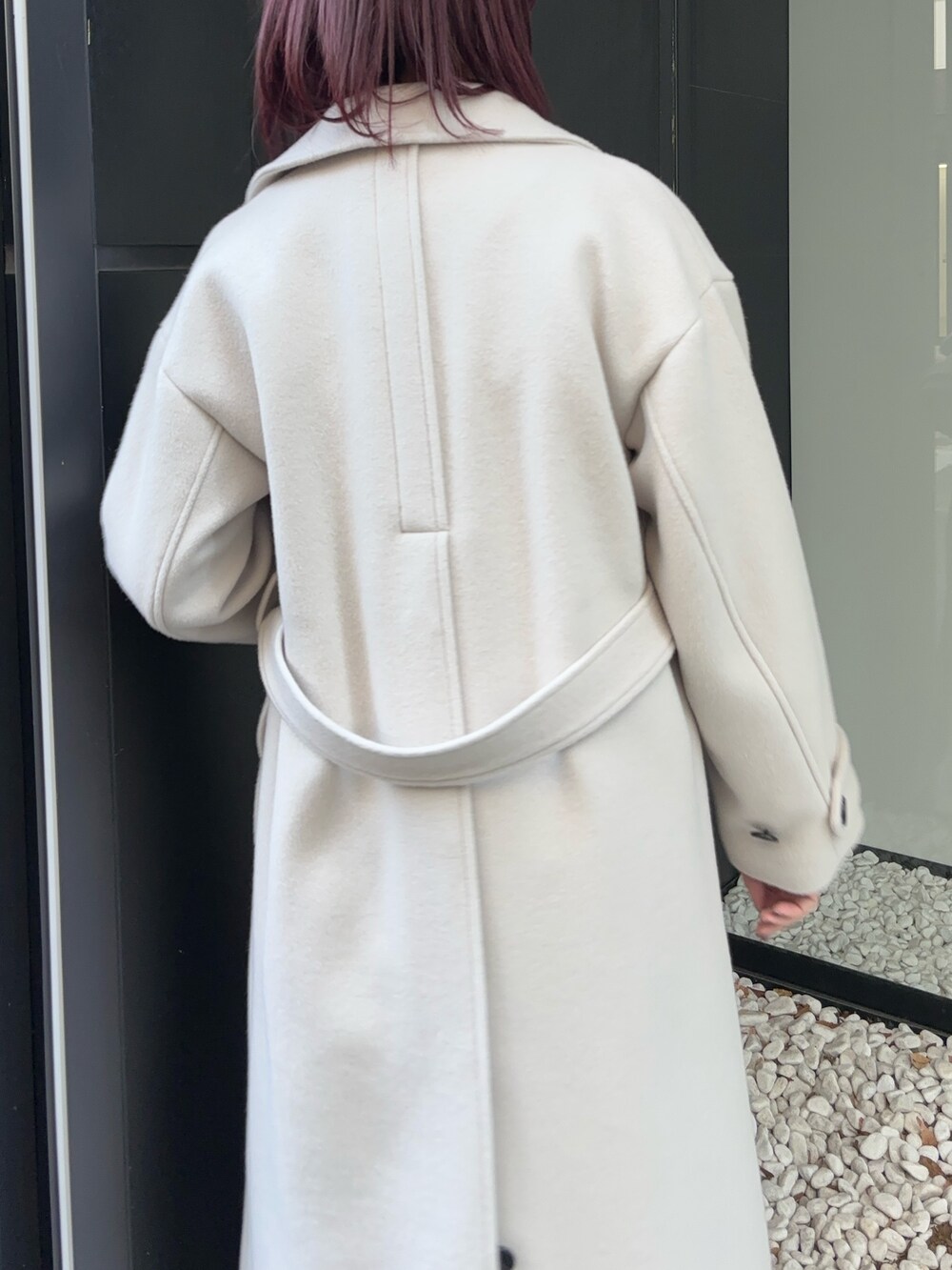 ホワイト系のステンカラーコートを着用したレディースの冬コーディネートの5枚目の写真