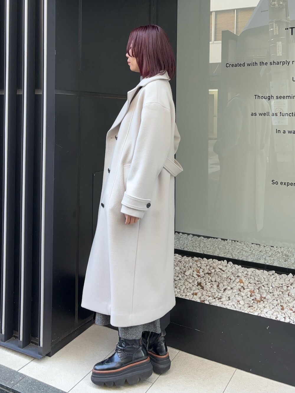ホワイト系のステンカラーコートを着用したレディースの冬コーディネートの3枚目の写真