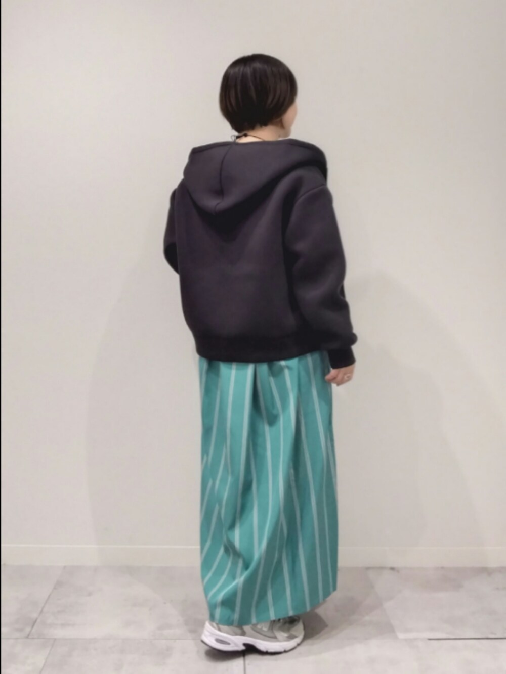 グリーン系のワンピース、ブラック系のパーカーを着用したレディースの春コーディネートの3枚目の写真