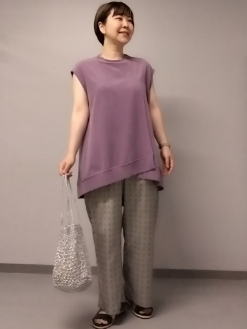 パープル系のTシャツ/カットソー、ベージュ系のその他パンツ、シルバー系のかごバッグを着用したレディースの夏コーディネートの2枚目の写真