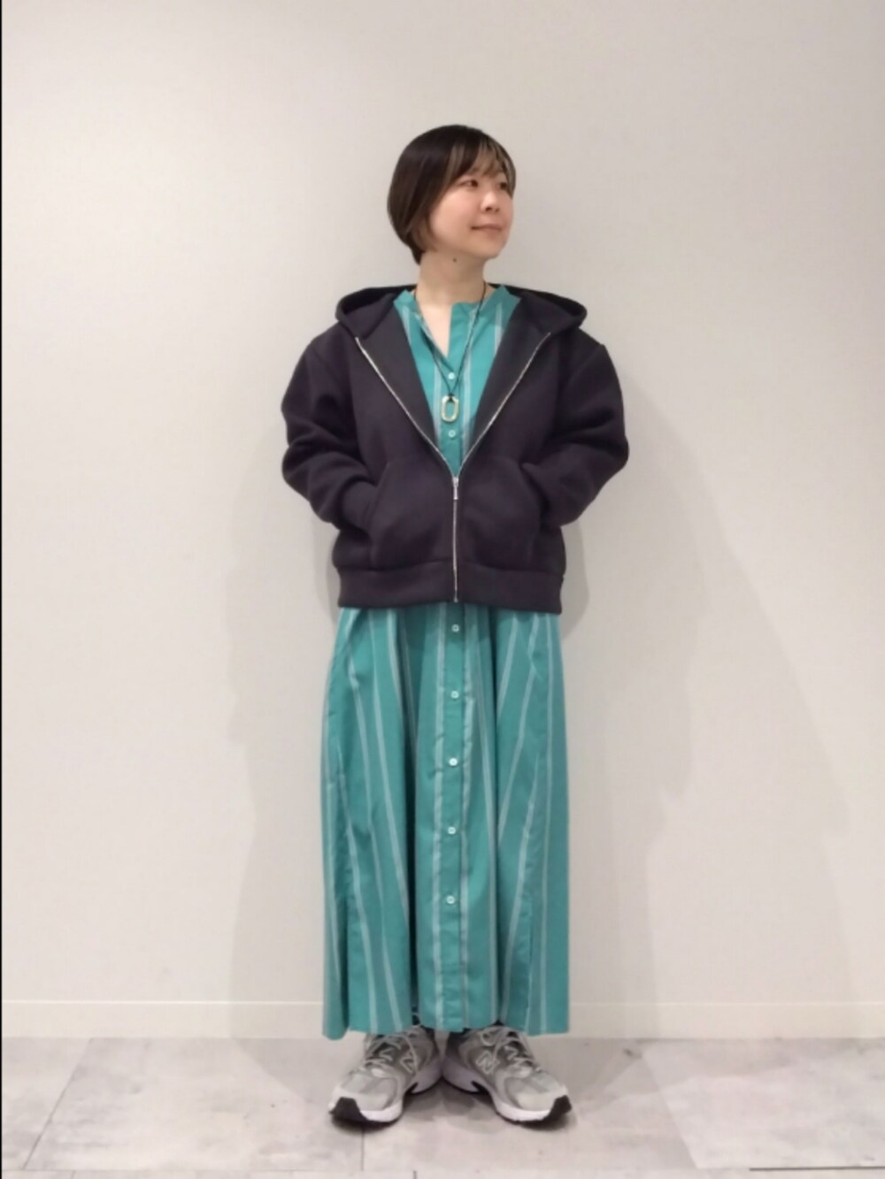 グリーン系のワンピース、ブラック系のパーカーを着用したレディースの春コーディネートの2枚目の写真