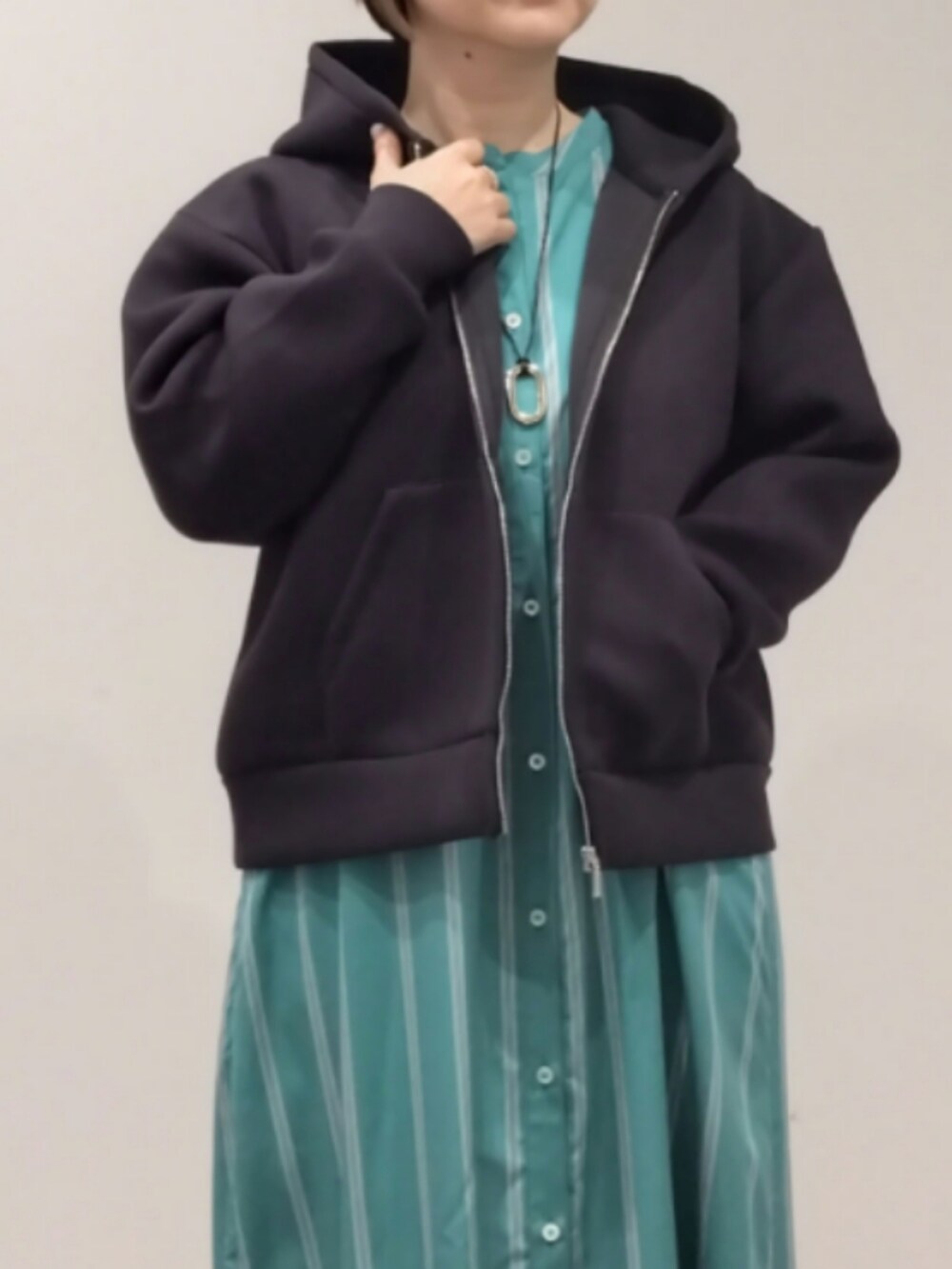 グリーン系のワンピース、ブラック系のパーカーを着用したレディースの春コーディネートの5枚目の写真