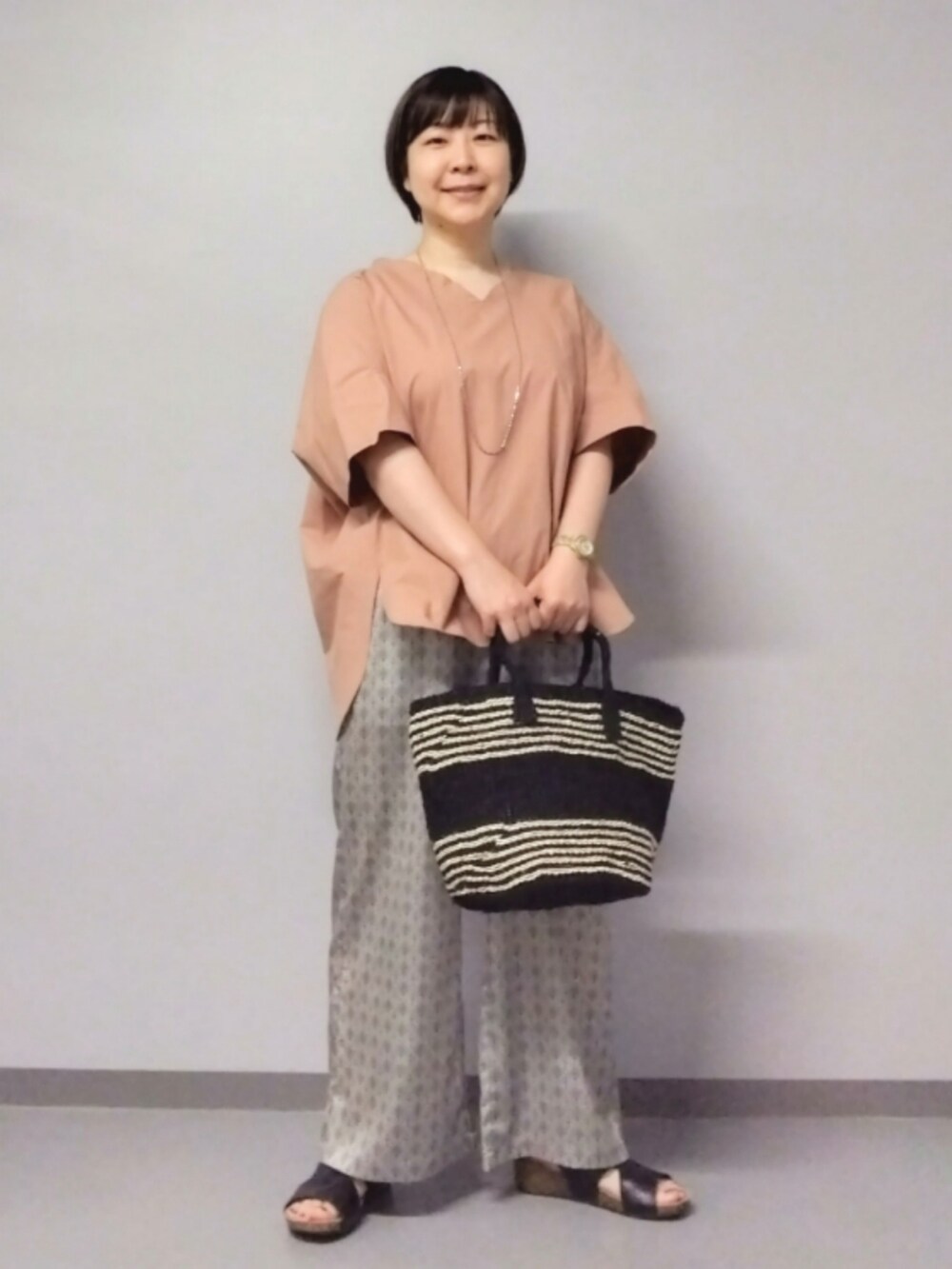 ベージュ系のその他パンツ、ブラック系のかごバッグ、ピンク系のシャツ/ブラウスを着用したレディースの夏コーディネートの2枚目の写真