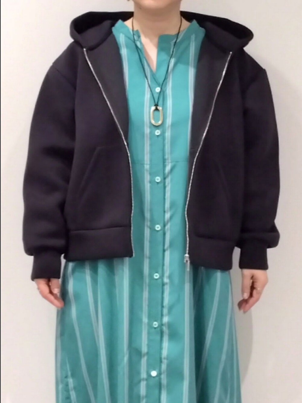 グリーン系のワンピース、ブラック系のパーカーを着用したレディースの春コーディネートの4枚目の写真