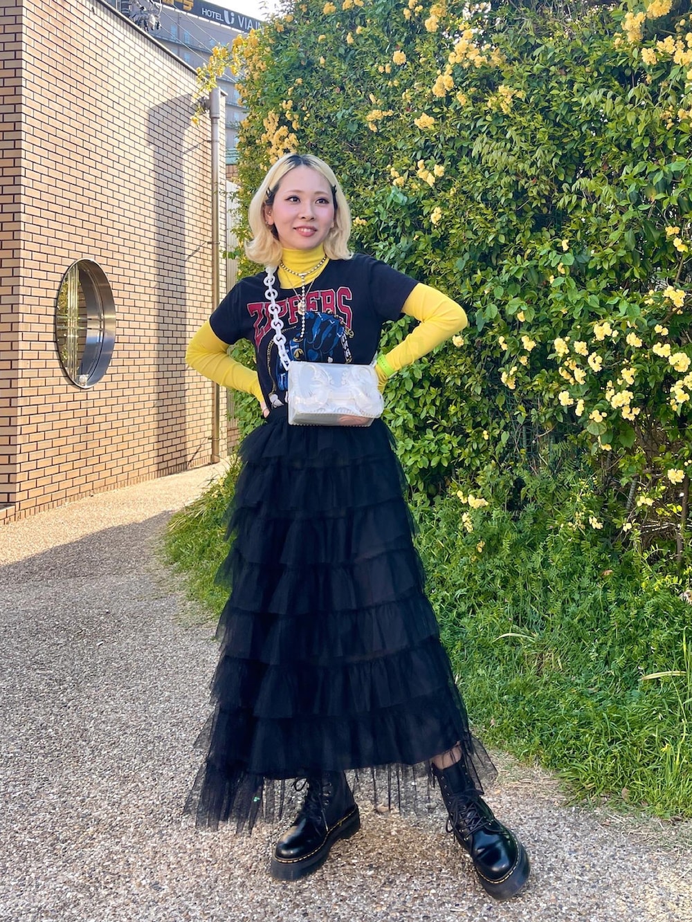 ブラック系のスカート、ホワイト系のハンドバッグ、ブラック系のTシャツ/カットソーを着用したレディースの春コーディネートの2枚目の写真